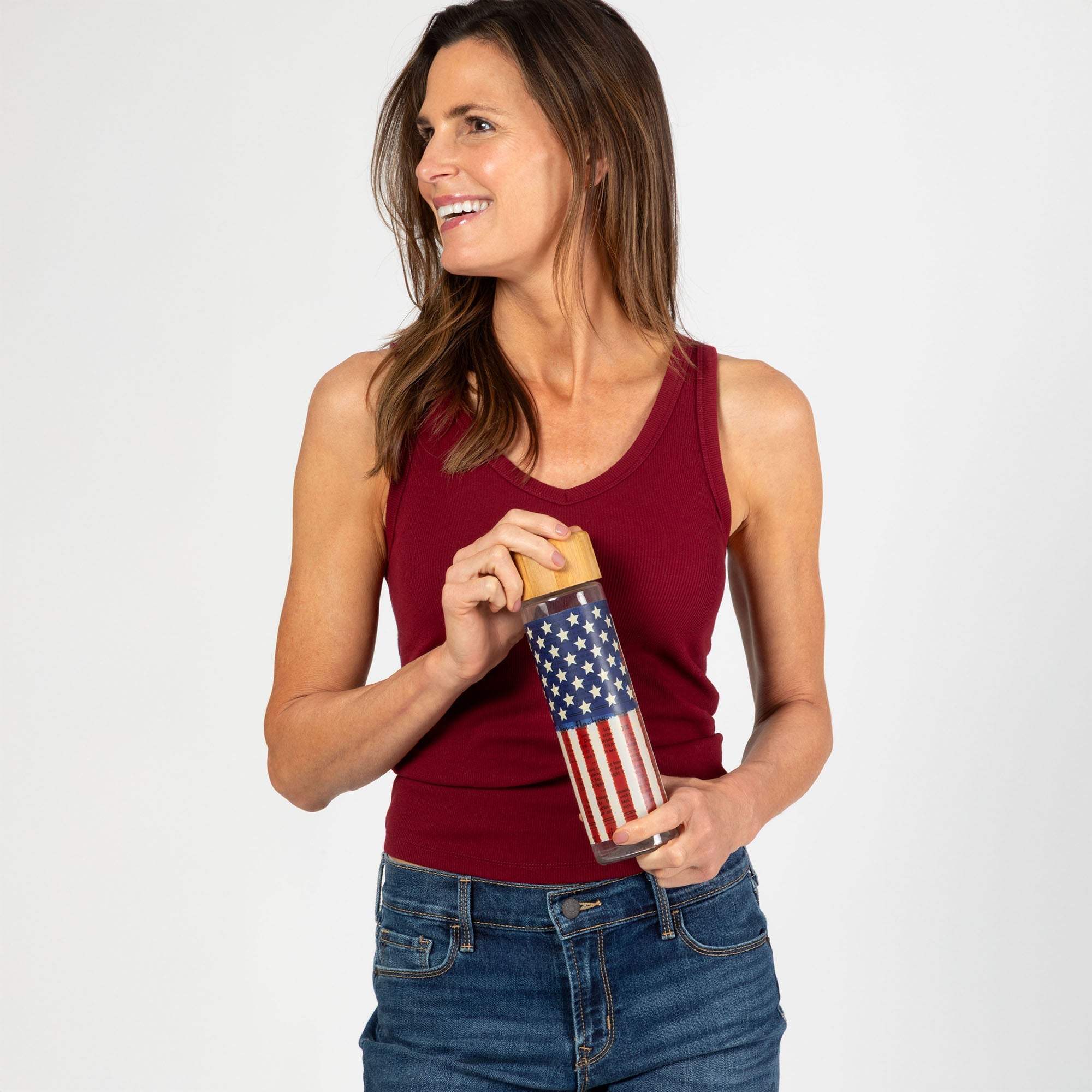 Woman holding patriotic star-themed glass water bottle with bamboo lid
